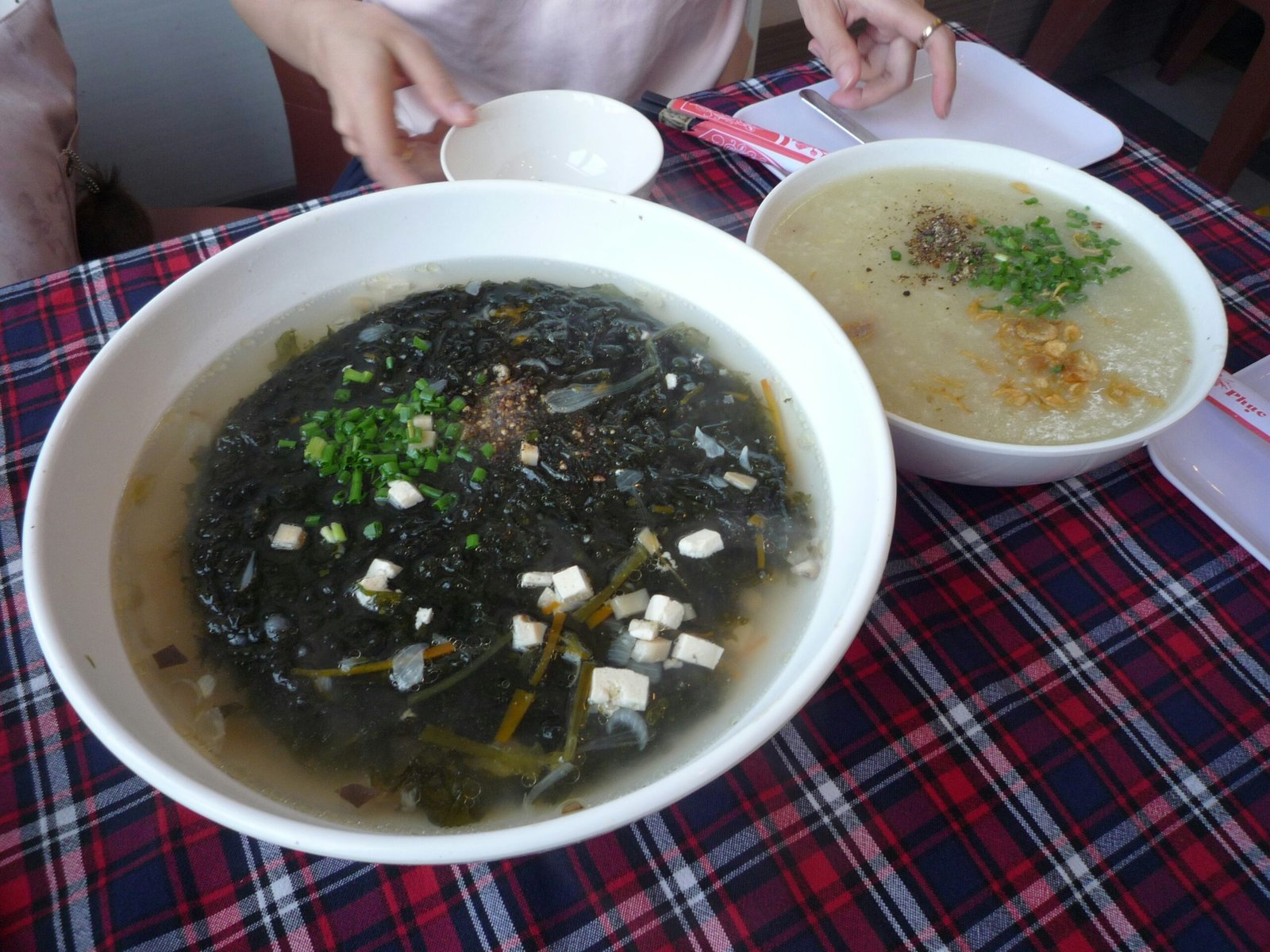 Bowl of rice porridge next to a bowl of soup at a table